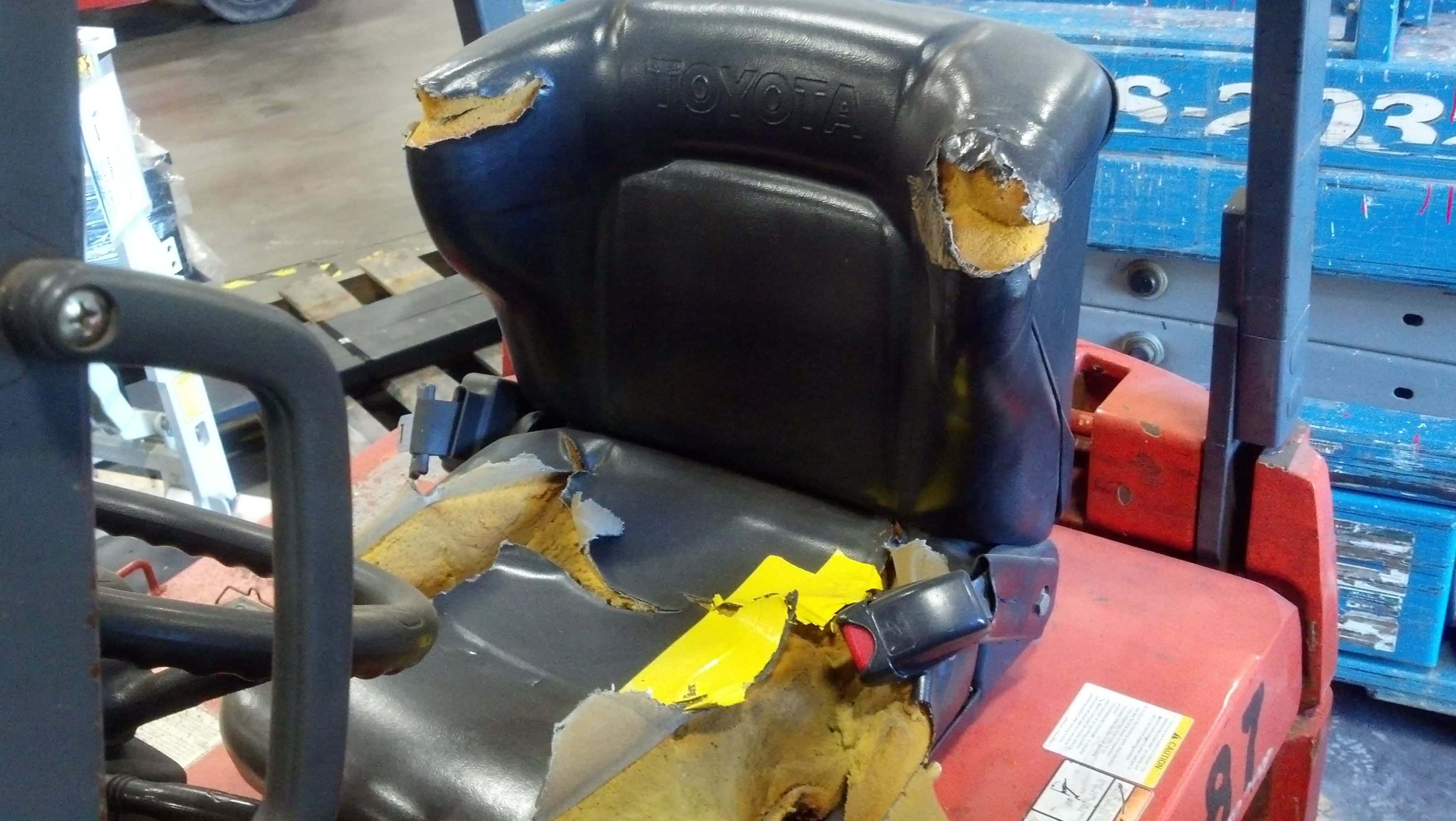 A destroyed Toyota forklift seat that needs to be replaced immediately.